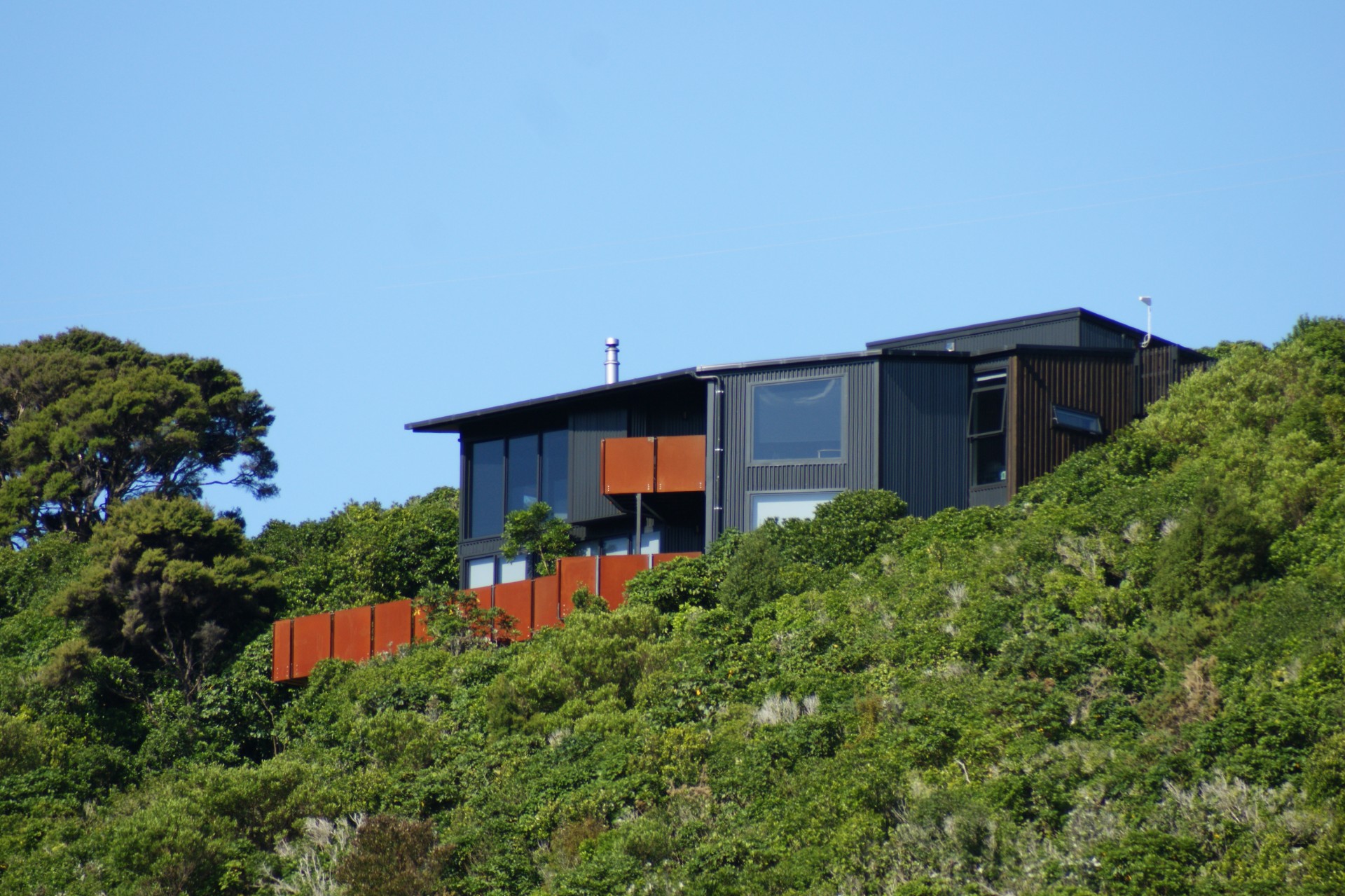 Front view of Tata Beach House perched on bush-clad hillside overlooking Golden Bay in the Tasman region