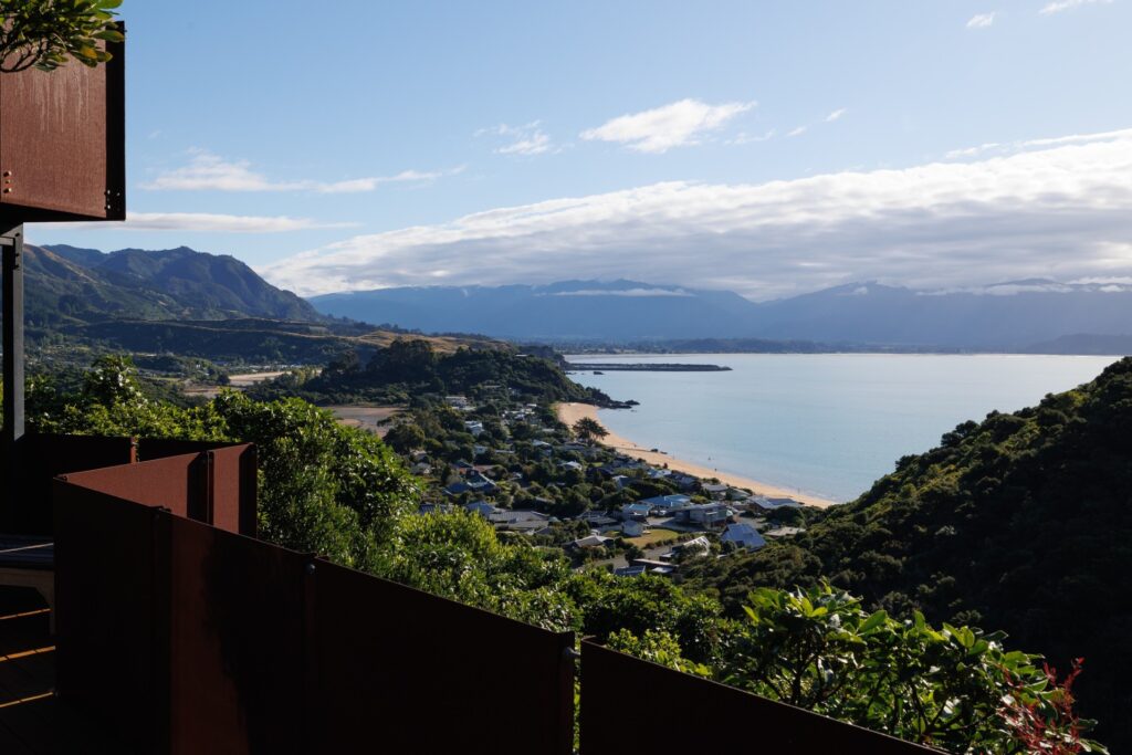 View across Tata Beach and Golden Bay from a corten-screened balcony in the canopy.