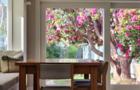 Dining area opening onto garden terrace through sliding glazed timber doors in Christchurch home