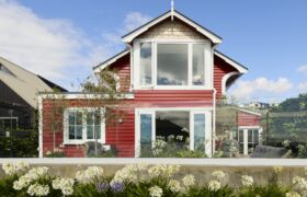 Waterfront view of The Red Cottage with French doors open to the deck