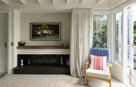 Sitting room with fireplace and soft drapery, opening through French doors to a sheltered deck and garden.