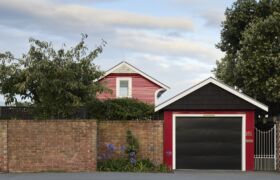 The Red Cottage street frontage behind brick wall, with garage and gable form retained as the familiar face of the home.