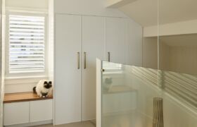 Upper landing with built-in cabinetry and window seat, looking down through glass to the pendant in the stairwell.