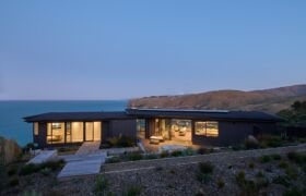 Scarborough House at dusk with warm interior lighting and decks overlooking the ocean