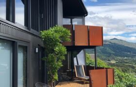 Wrap-around deck of Tata Beach coastal home with sea views and native bush surroundings