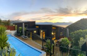 Sheltered rear pool deck surrounded by native bush at Tata Beach coastal retreat