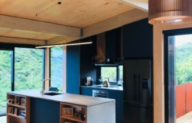 Interior living area showing exposed cross-laminated timber structure and natural light in Tata Beach House