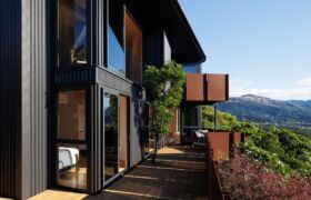 Exterior deck along dark cladding, with corten lookout balconies projecting over the bush.