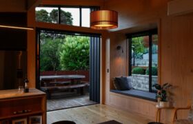 Living area with window seat and sliding doors opening to a sheltered deck and courtyard planting.