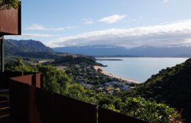 View across Tata Beach and Golden Bay from a corten-screened balcony in the canopy.